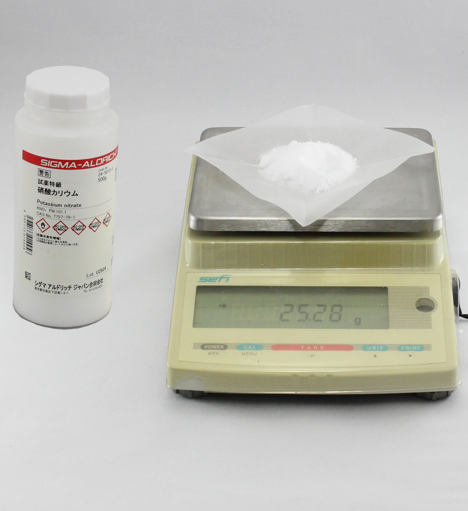 Fig. 2 Weigh the potassium nitrate (1) using folded and creased weighing paper (2) with an electronic balance.